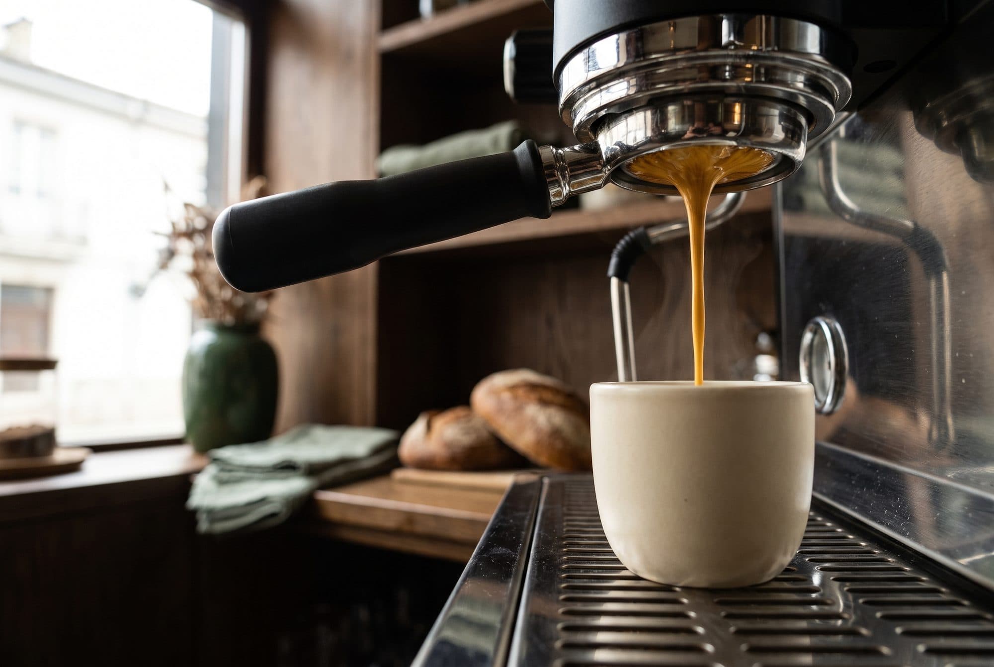 Un espresso cayendo del portafiltro a una taza de cerámica